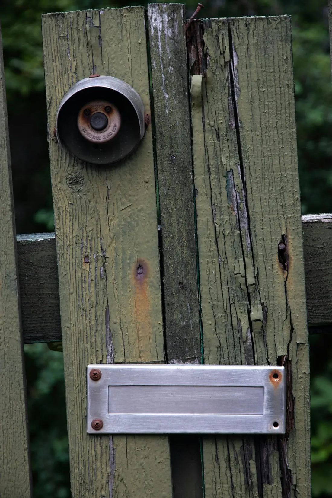 Old wooden gate with doorbell and mail slot.