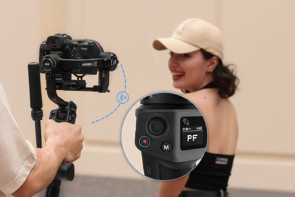 Camera stabilizer with close-up of control panel held by a person, with a woman in the background.