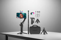 Gaming streaming setup with smartphone, selfie stick, RGB light, and carrying case on a white background